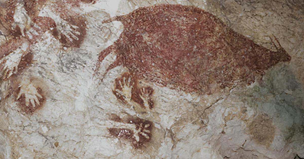 Ciervos rojos salvajes y plantillas de manos en pinturas rupestres prehistóricas de la cueva Sumpang Bita