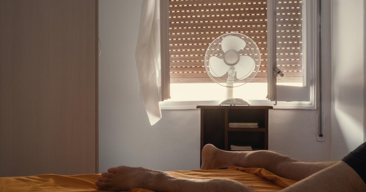 Imagen de una persona sufriendo una ola de calor en la habitación de una vivienda.