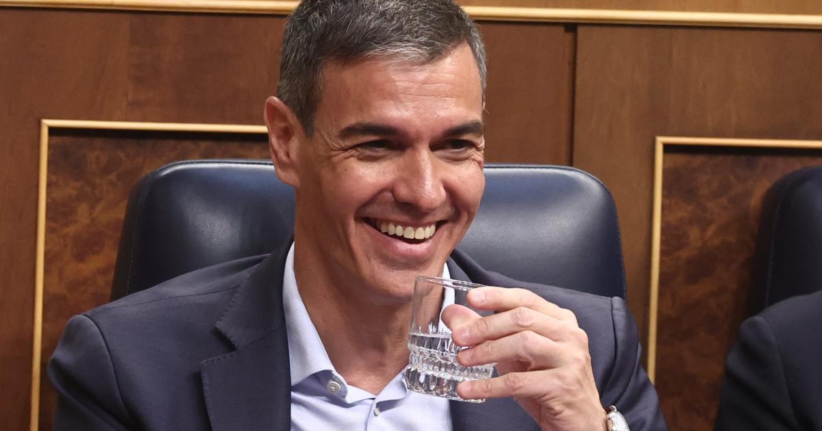 El presidente del Gobierno, Pedro Sánchez, riéndose en el Congreso, con un vaso de agua en la mano.