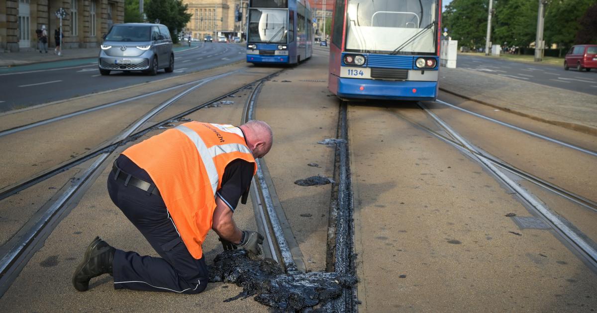 Un operario se afana en retirar el material sellante de la red de tranvía que se ha derretido por la ola de calor en Leizpig, Alemania, durante junio de 2026