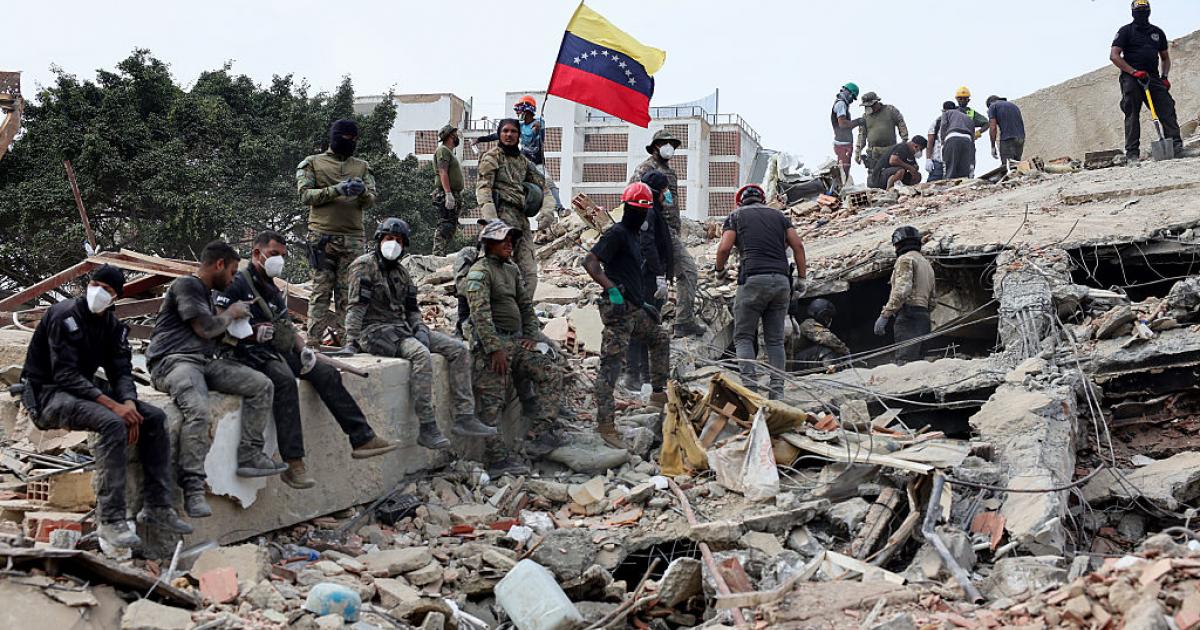 Los equipos de rescate colocan una bandera de Venezuela sobre los escombros, tras el doble terremoto sufrido por el país, el 28 de junio de 2026, en Caracas.