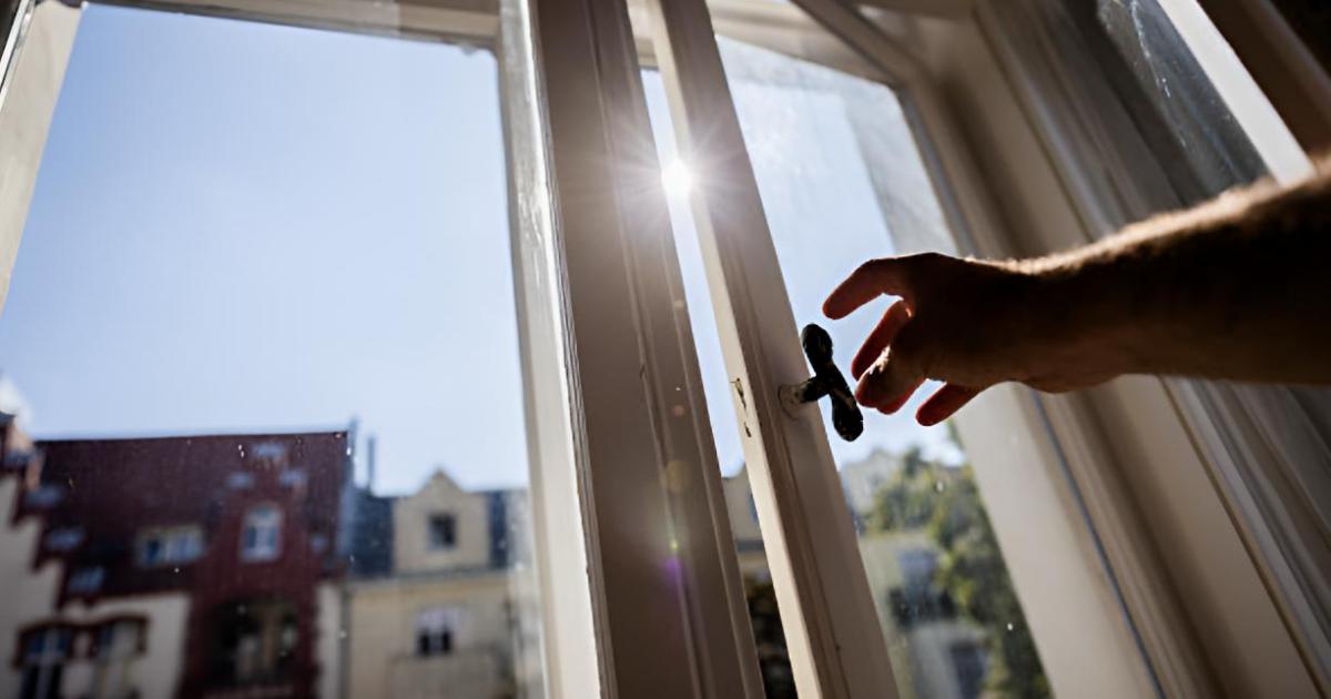 Una persona cerrando la ventana de casa para que no entre el calor
