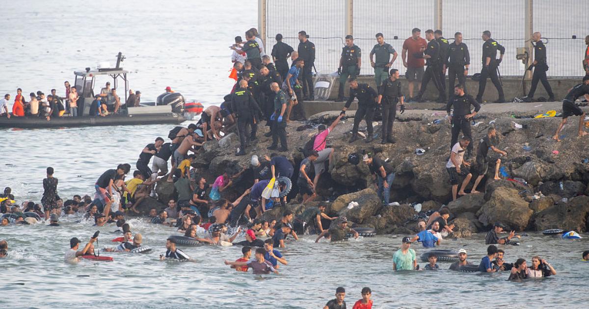 Cientos de personas de origen magrebí cruzan a Ceuta desde Marruecos, ya sea nadando o escalando el rompeolas, el 30 de julio de 2026.