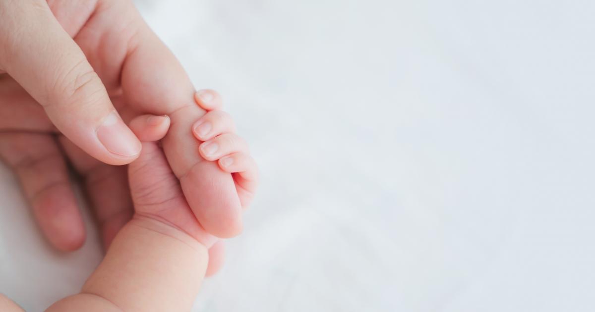 Una madre le sujeta la mano a un bebé recién nacido