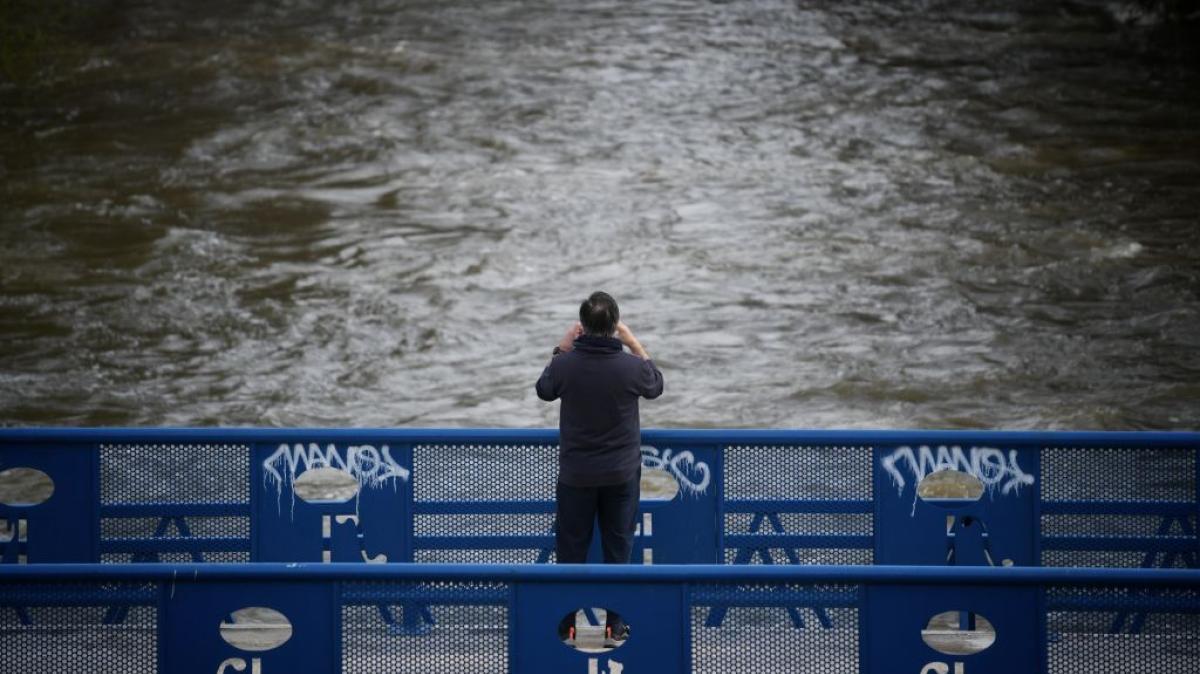Una persona fotografía el curso del río de Manzanares, crecido por las intensas lluvia que trae la borrasca Martinho.