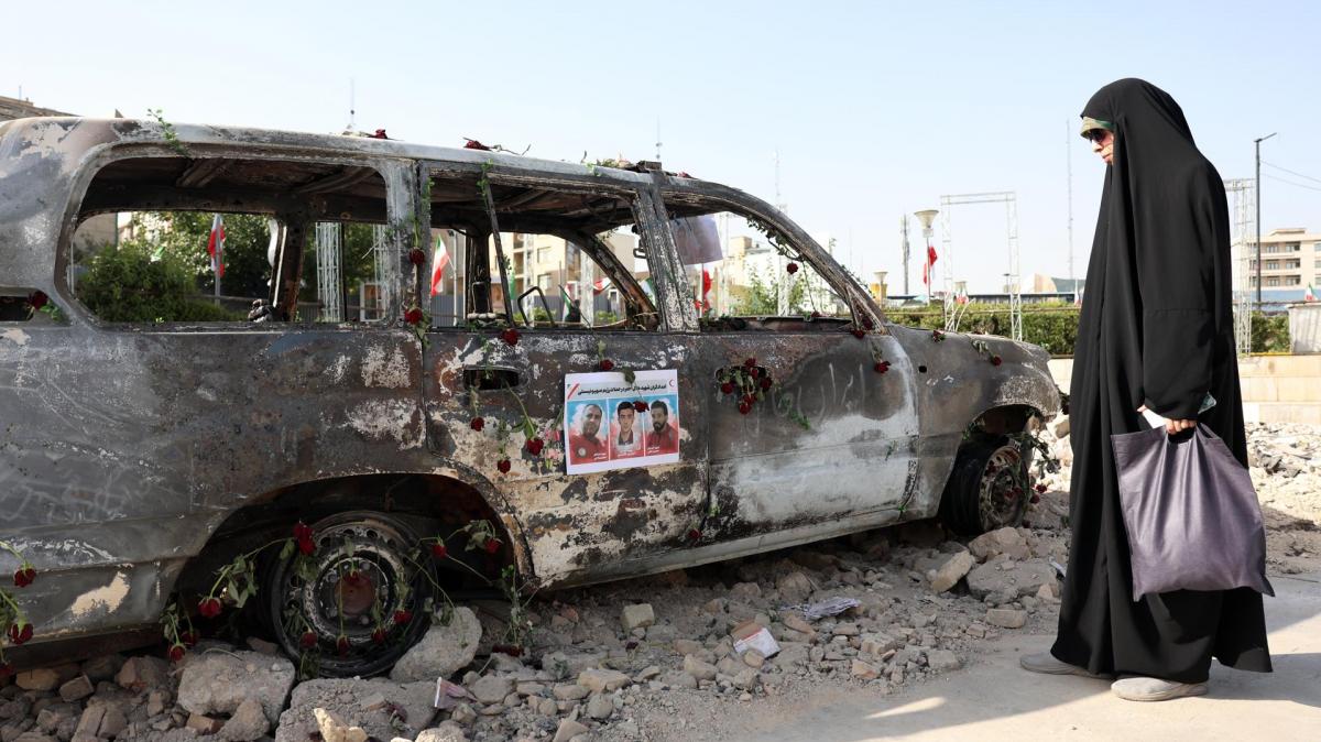 Una mujer iraní con velo, junto a una ambulancia de la Media Luna Roja destruida en un ataque de Israel.