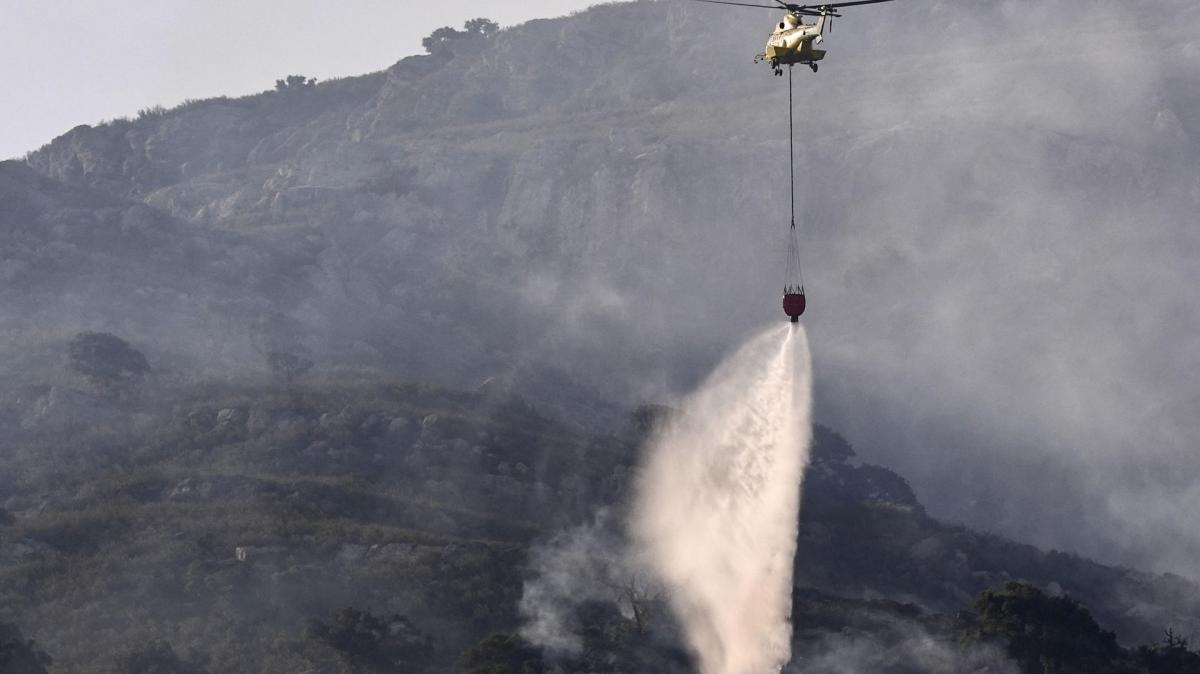 Un helicóptero trabaja en las labores de extinción del incendio que desde este lunes afecta a la Sierra de la Plata, en Tarifa (Cádiz).