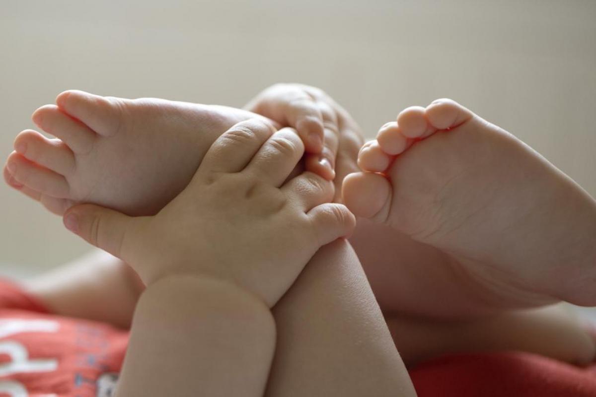 Primer plano de un bebé asturiano agarrándose los pies