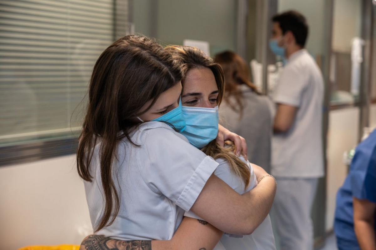 Dos sanitarias se abrazan dentro de un hospital