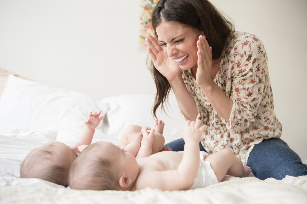 Una mujer jugando al cucú-tras con sus bebés.