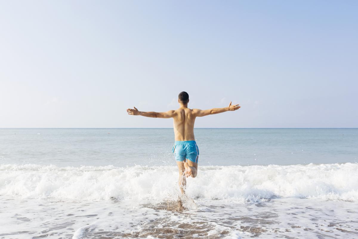 Un hombre en bañador entrando en el mar.