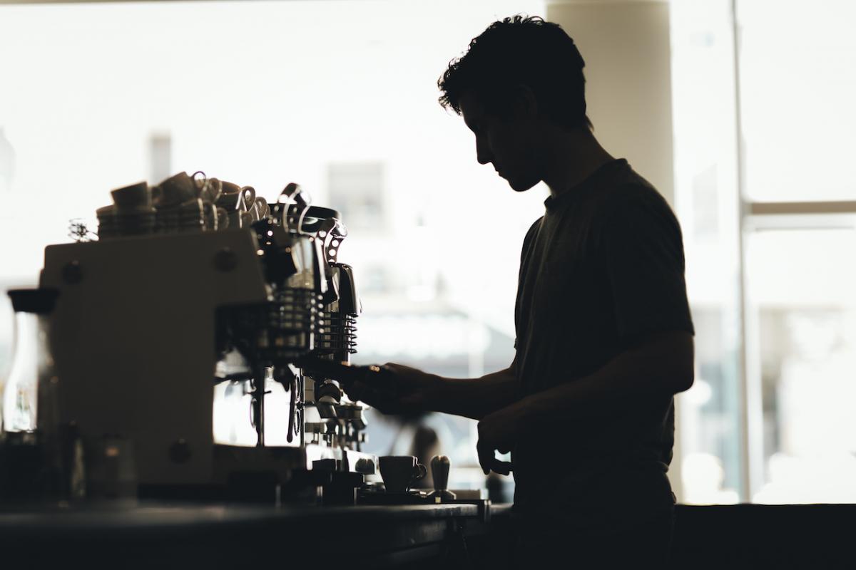 La silueta de un barista preparando café en una cafetería.