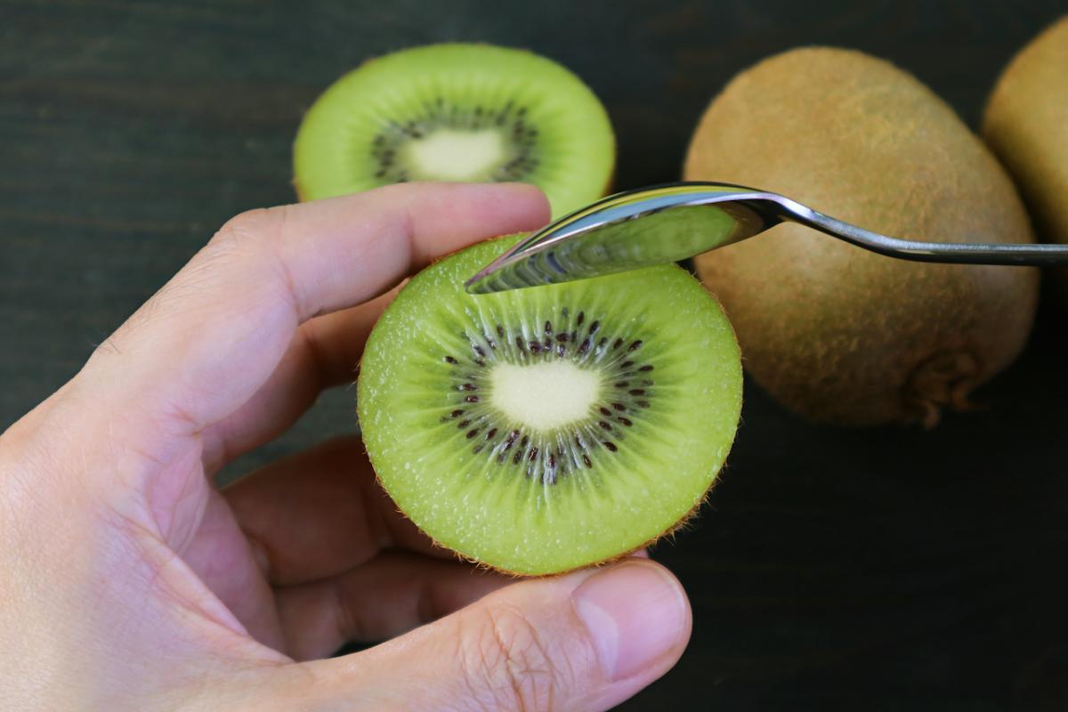 Una persona se prepara para comer un kiwi a cucharadas.