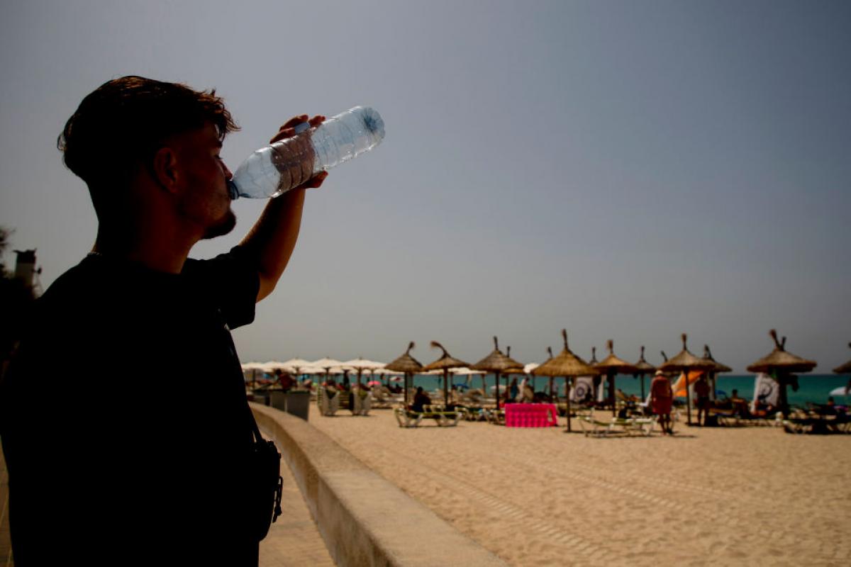 Un joven apura una botella de agua en una playa de Mallorca