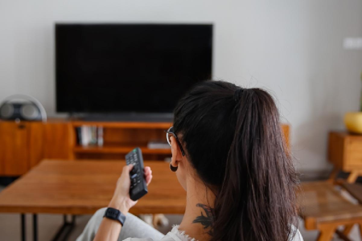 Una mujer encendiendo su televisión