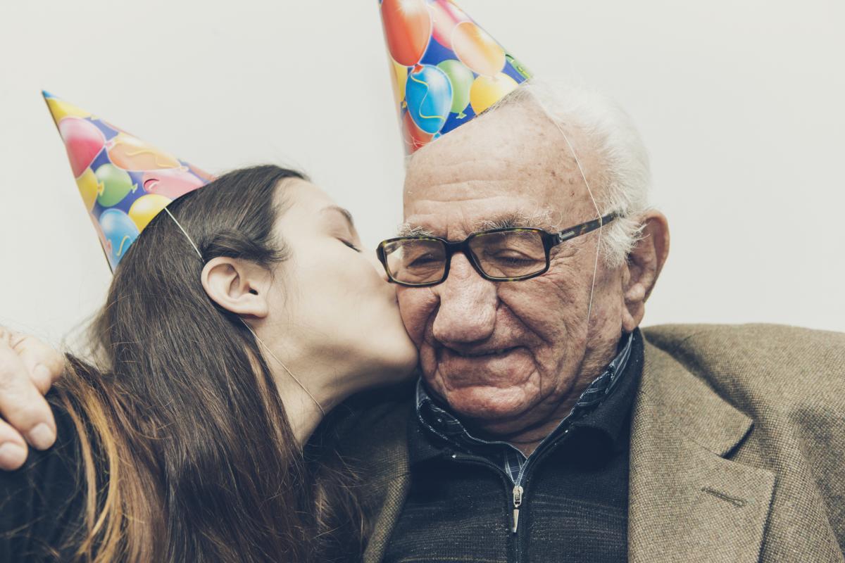 Imagen de archivo de un abuelo recibiendo un beso de su nieta.