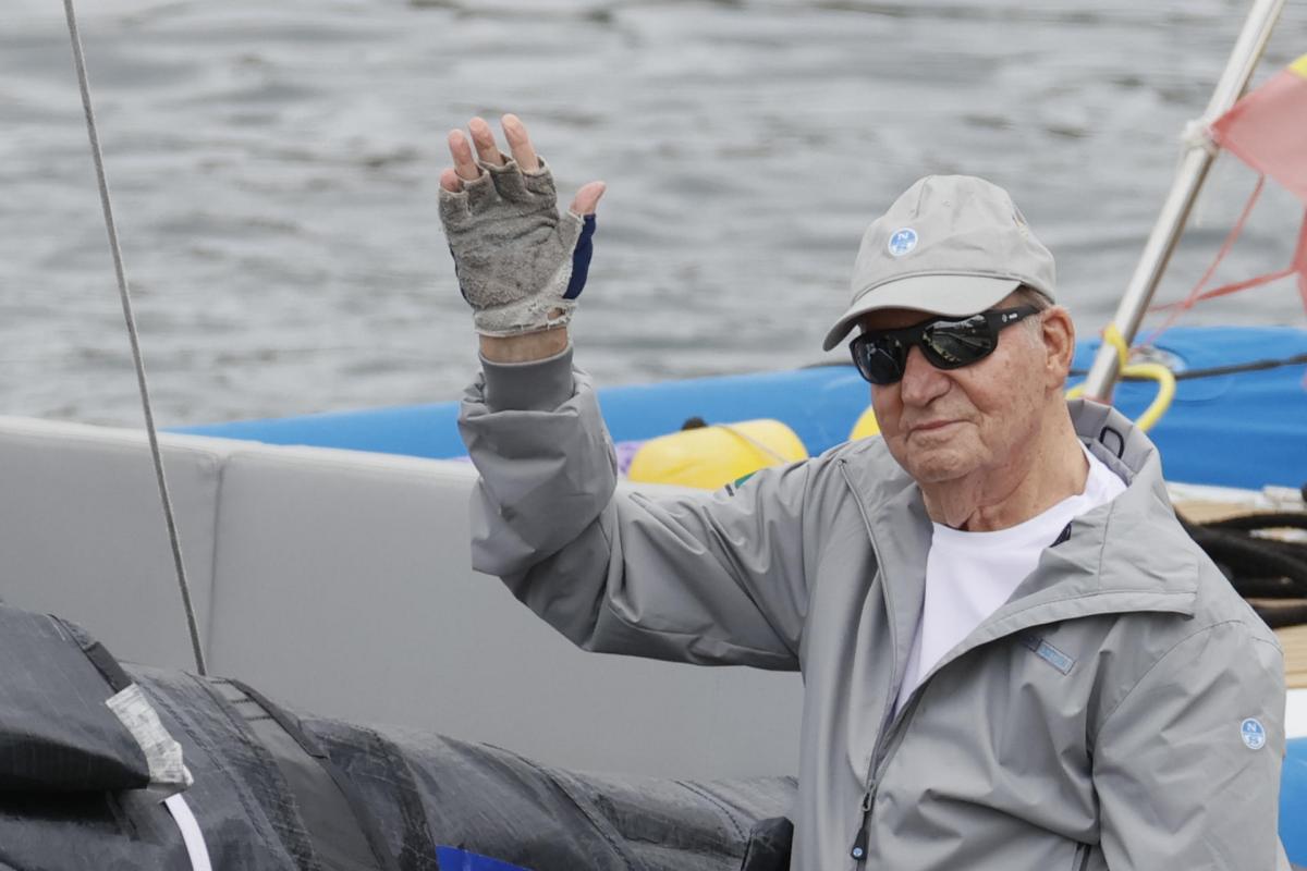 El rey emérito Juan Carlos I saluda desde la embarcación a su llegada este jueves al Real Club Náutico de Sanxenxo.