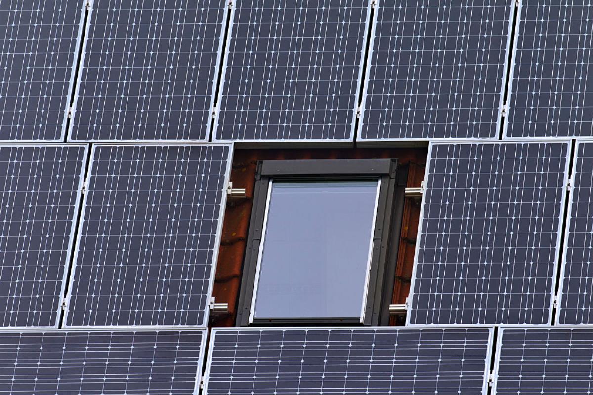 Paneles solares instalados en el tejado de una vivienda rodean una ventana.