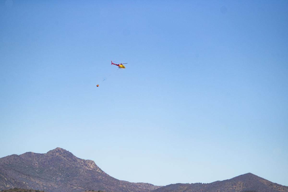 Un helicóptero sobrevuela la zona afectada por el fuego en Portbou (Girona) este sábado.