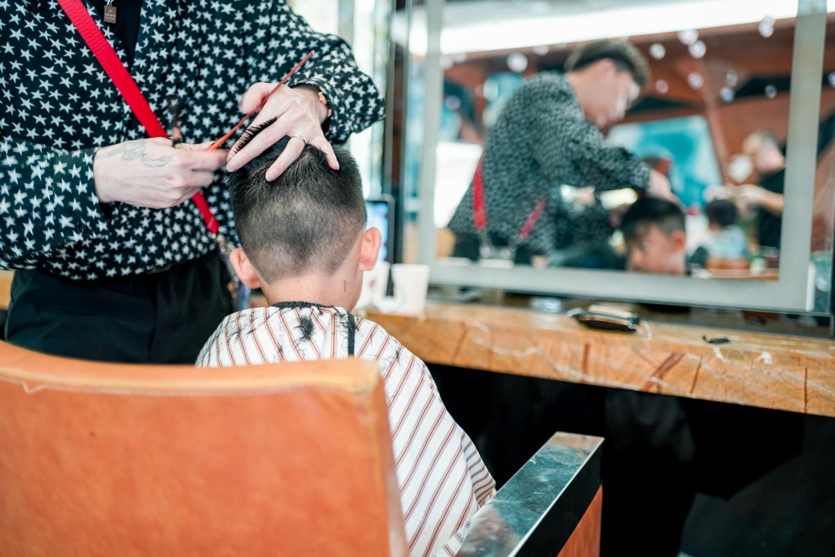 Foto de archivo de un peluquero cortándole el pelo a un niño