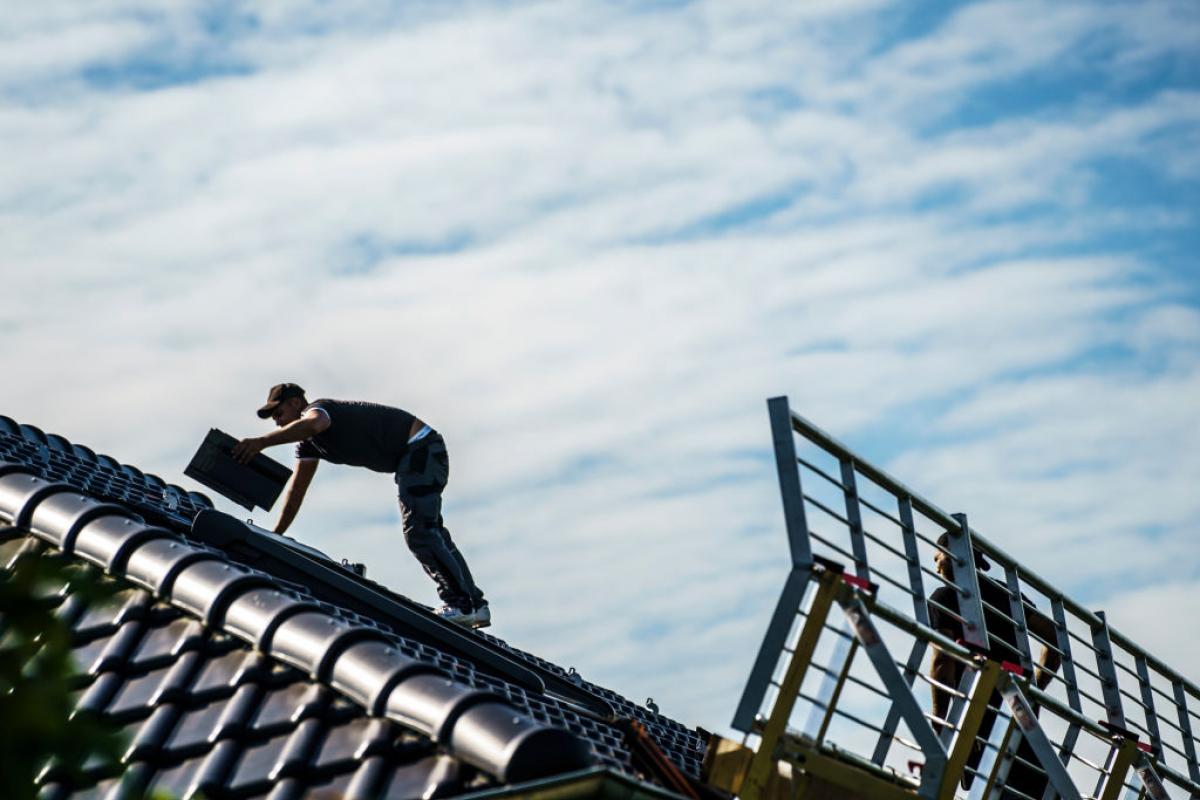 Imagen de archivo de un hombre instalando placas solares en el tejado de una vivienda.
