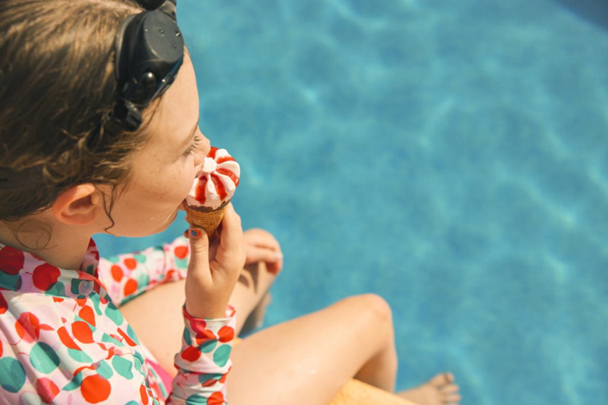 Una chica come un helado en una piscina en una imagen de archivo.