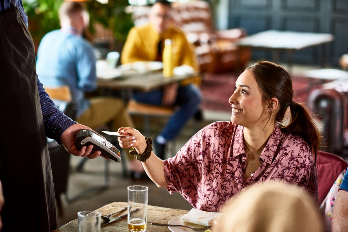 Imagen de archivo de una mujer pagando con tarjeta en un bar.