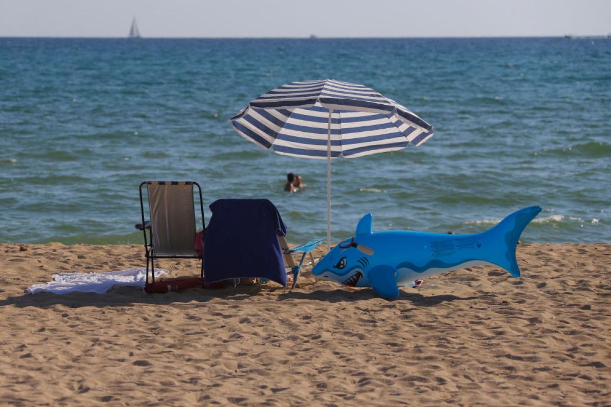 Un flotador con forma de tiburón junto a una silla y una sombrilla de playa en Palma de Mallorca en una foto de 2020.