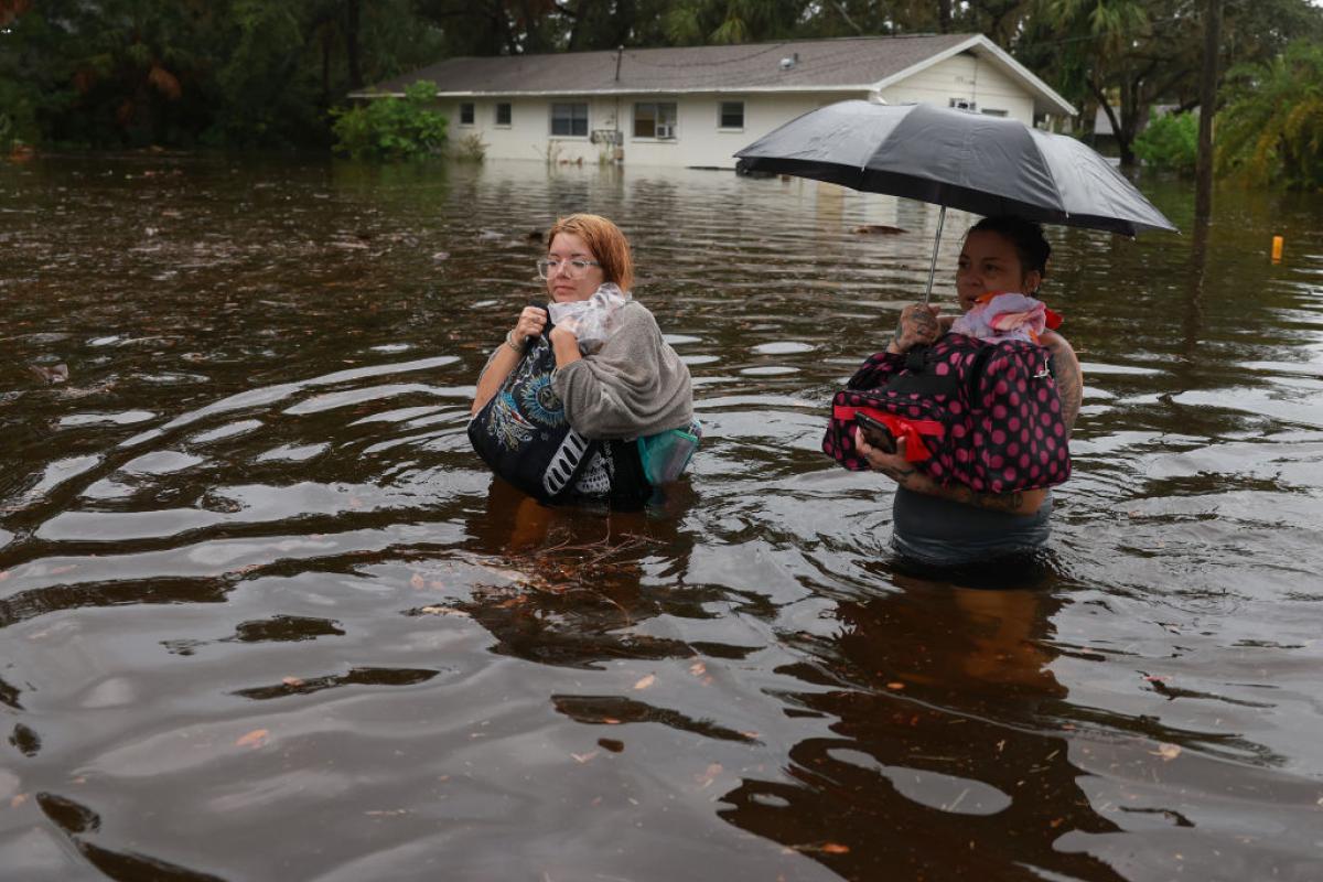 Dos mujeres, con el agua por la cintura, caminan por una ciudad de Floridad tras el paso del huracán Idalia.