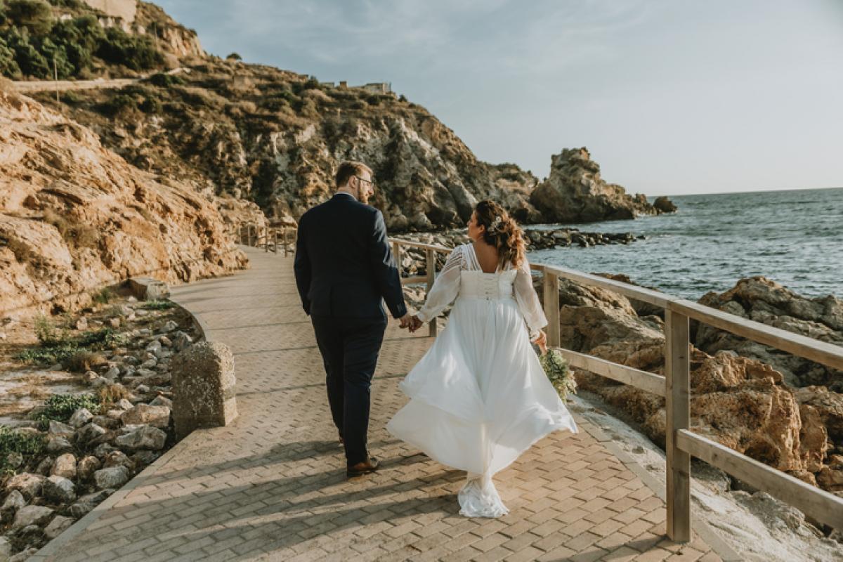 Dos personas recién casadas dan un paseo junto al mar en una imagen de archivo.