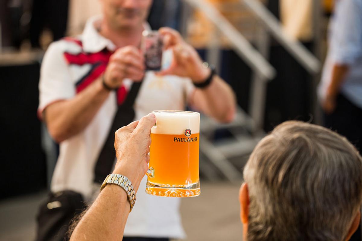 Un hombre saluda con una cerveza mientras otro le hace una foto en el Oktoberfest de Barcelona en una imagen de archivo.