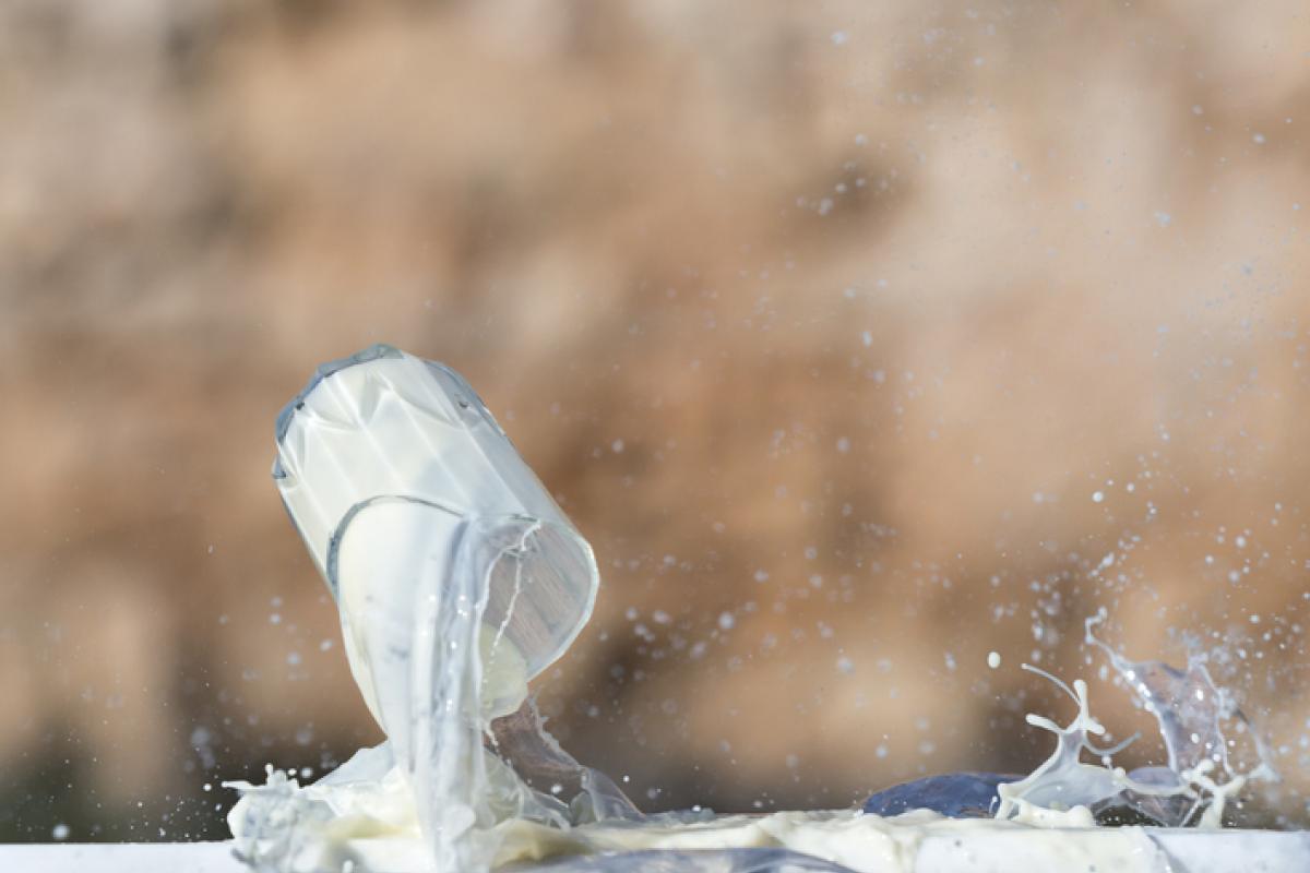 Un vaso lleno de leche cayendo al suelo en una imagen de archivo.
