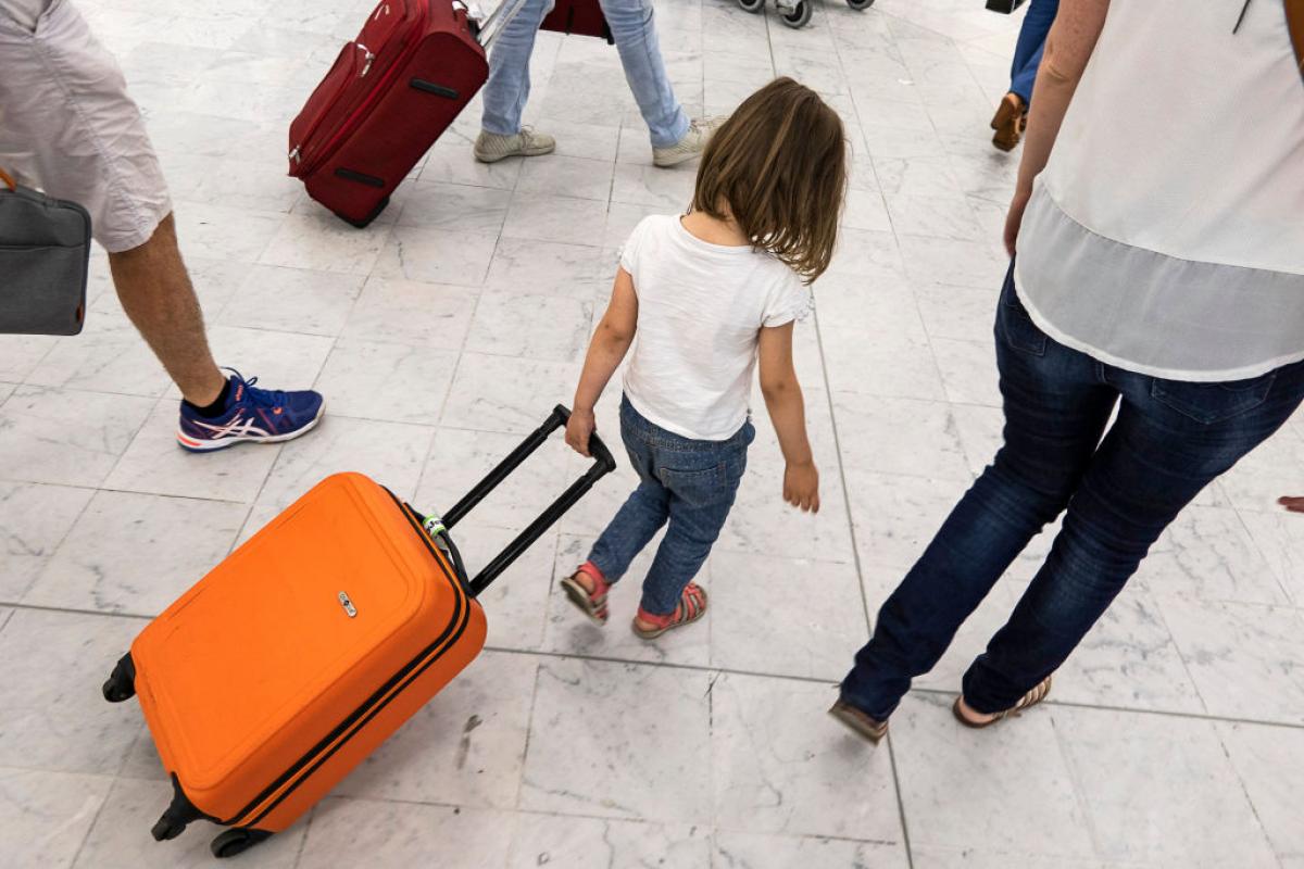 Una niña arrastra su maleta de mano por un aeropuerto en Europa.