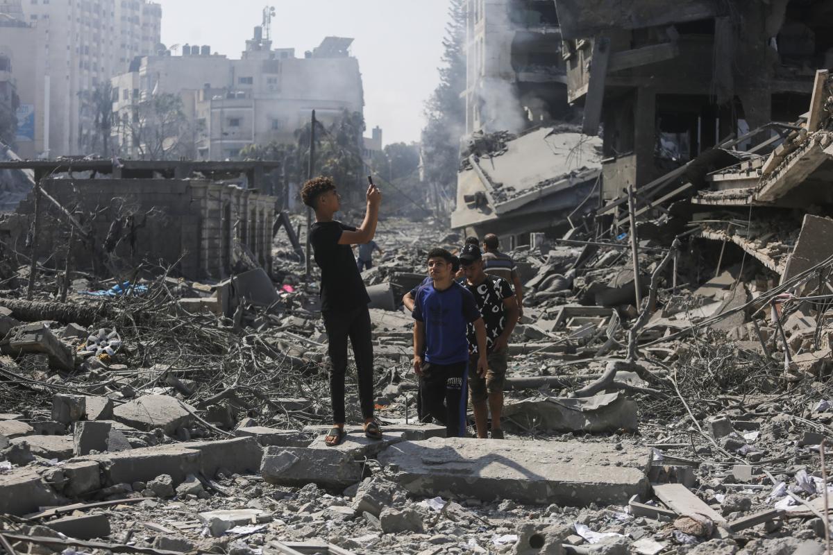 Jóvenes palestinos haciendo una fotografía tras el ataque israelí a un edificio en Gaza.