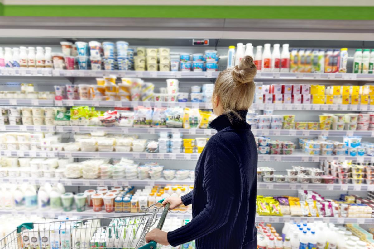 Una mujer eligiendo yogures en un supermercado.