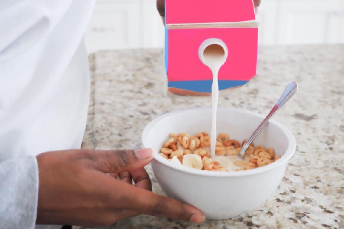 Una persona echando leche en su tazón de cereales