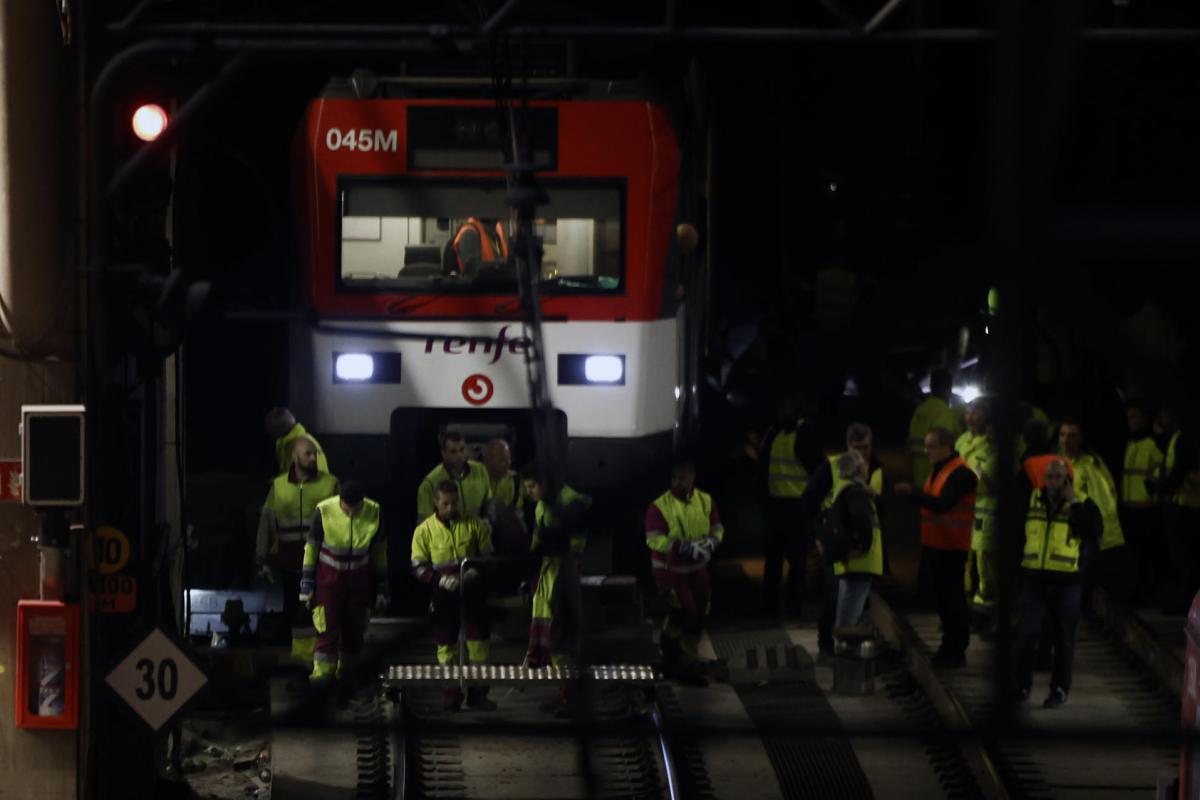 Varios operarios junto al tren de Cercanías que ha descarrilado este martes