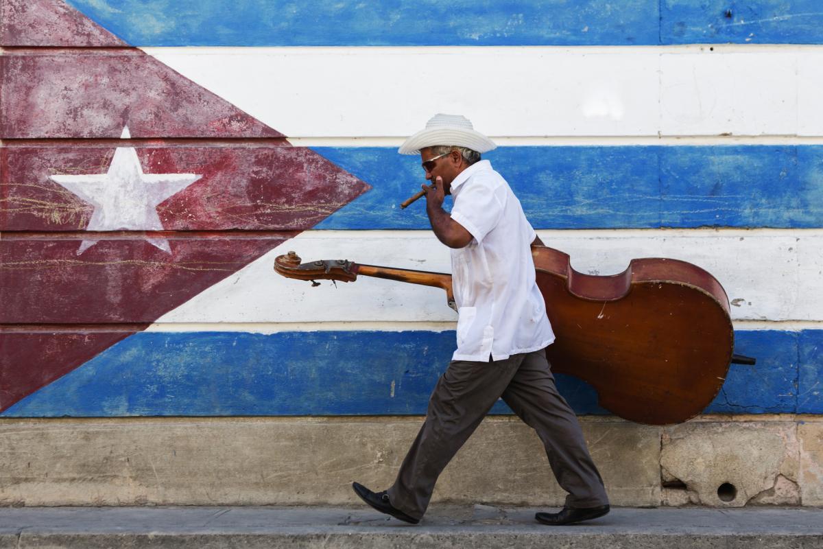 Un músico frente a un mural con la bandera de Cuba.