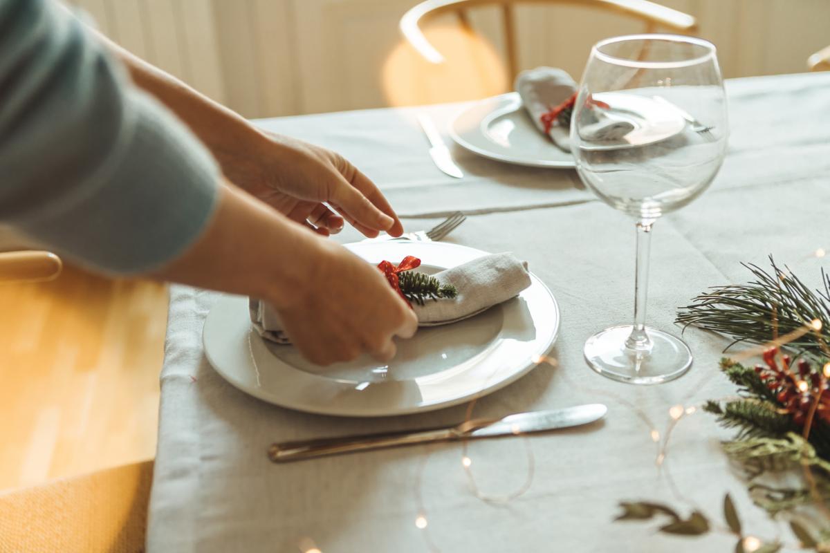 Una persona preparando la mesa para una comida navideña.