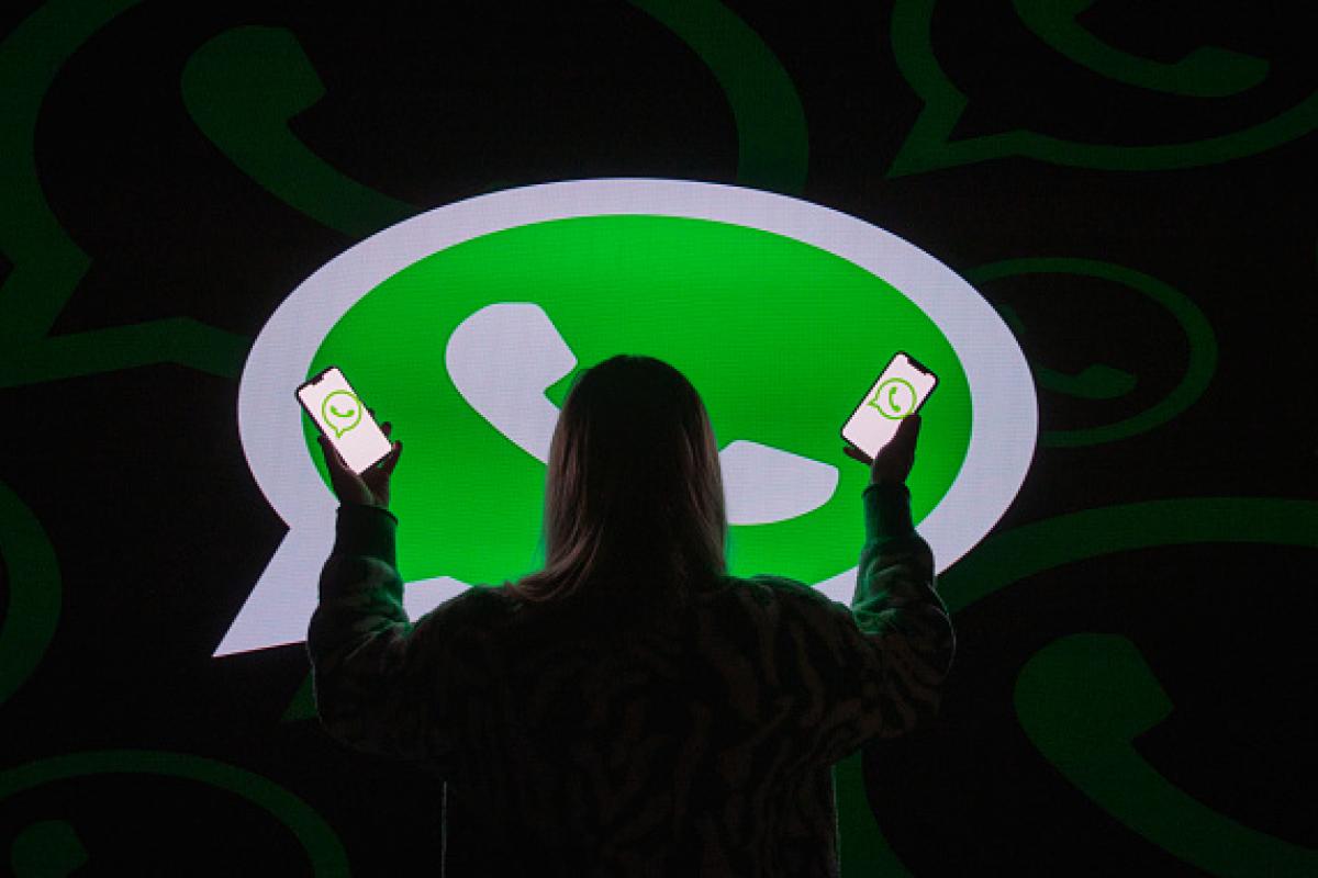 Una mujer, ante el logotipo de WhatsApp proyectado en el suelo.