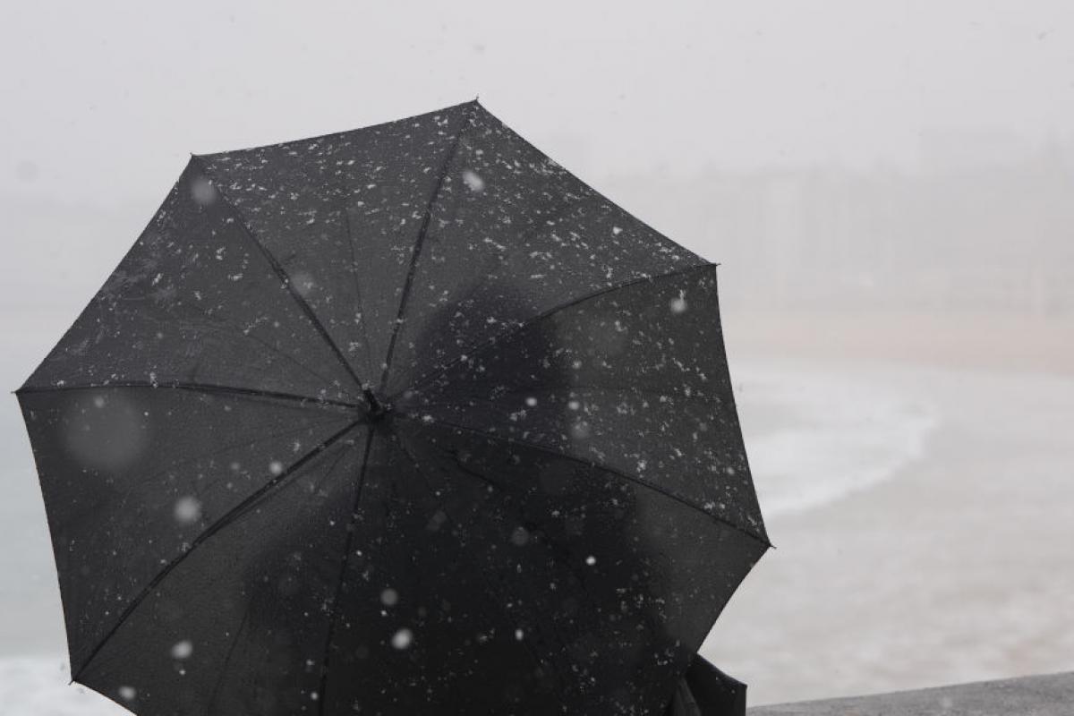 Una persona se protege del frío y el viento con un paraguas