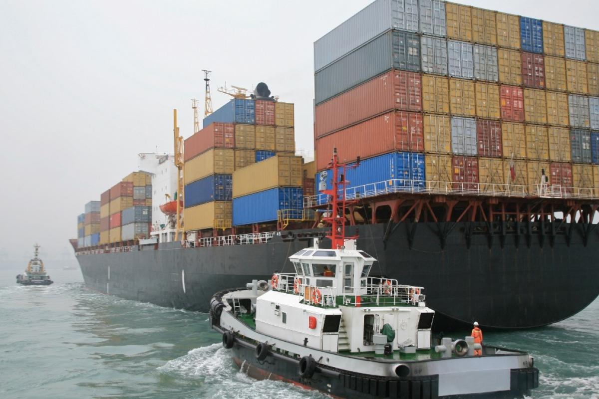 Remolcador navegando junto a un buque portacontenedores en China