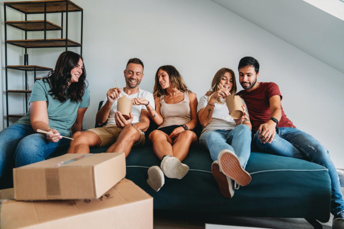 Imagen de archivo de varios jóvenes compañeros de piso, de mudanza, aprovechando una pausa para comer.