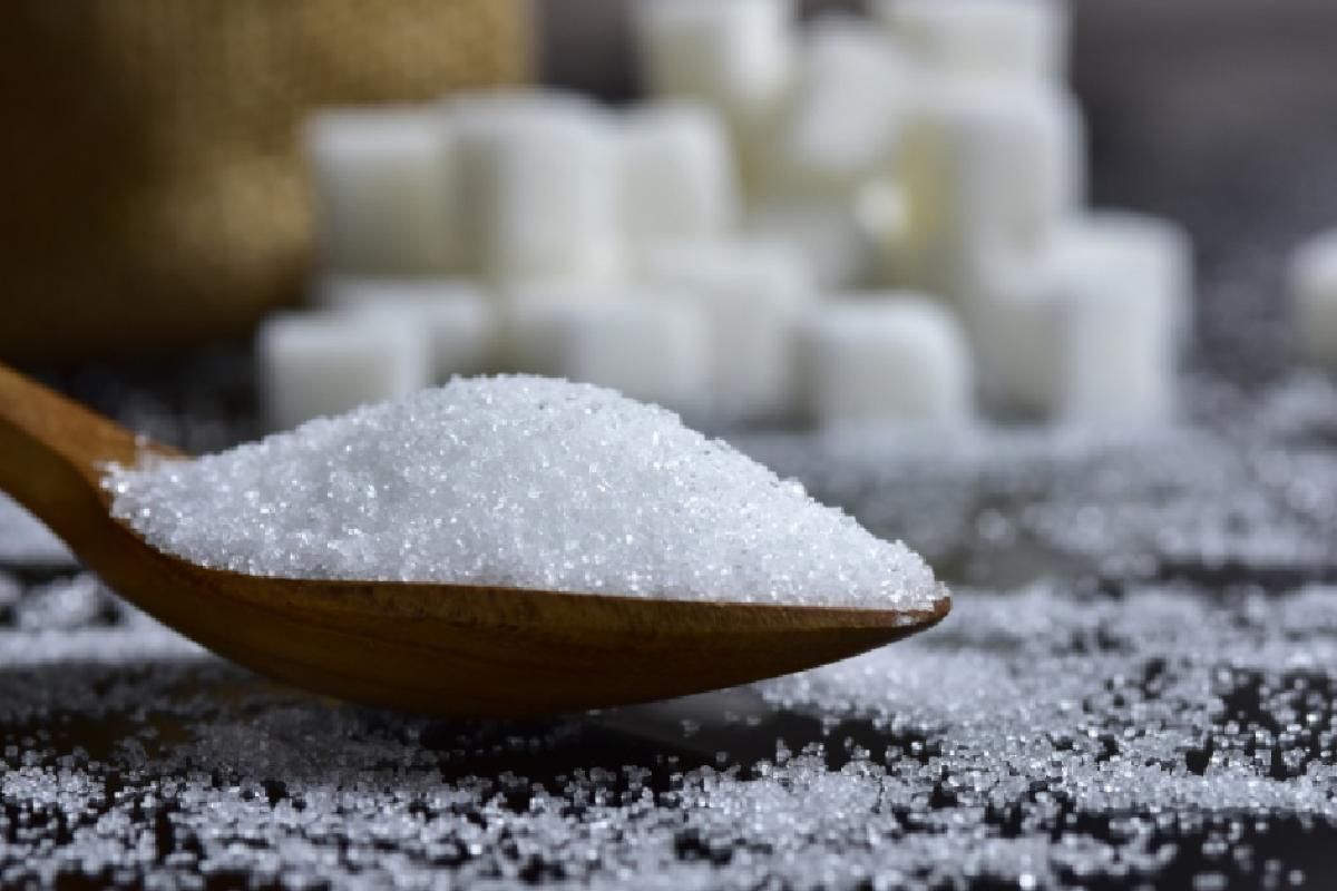 Cucharada de azúcar con terrones de fondo.