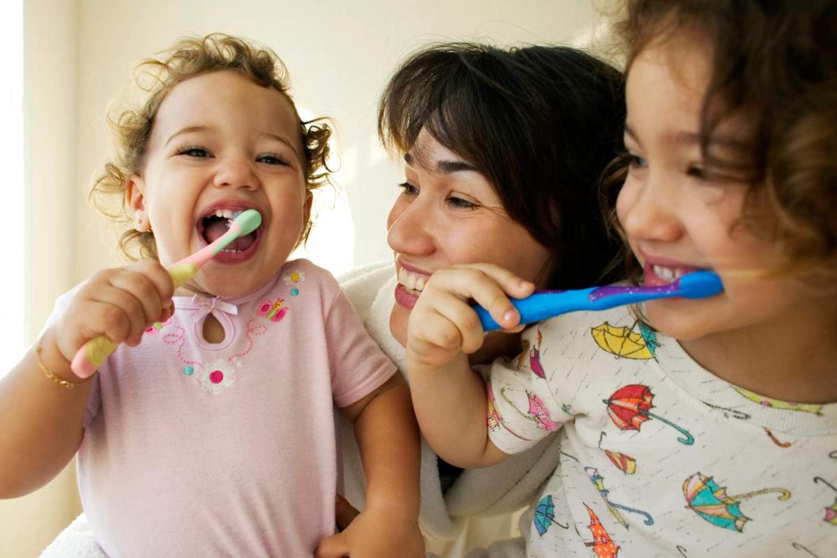 Niños cepillándose los dientes con su madre