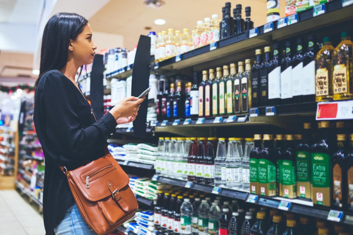 Imagen de una mujer comprobando varias marcas de aceite de oliva en un supermercado.