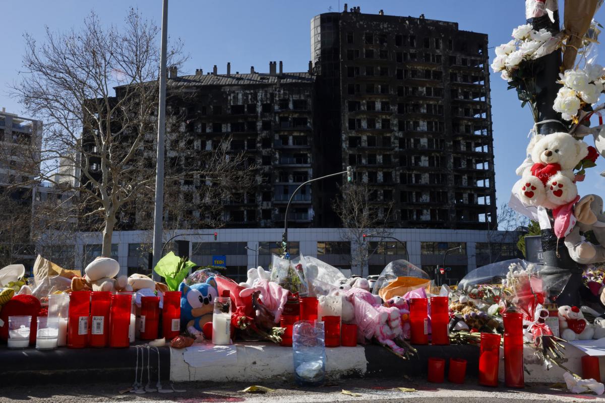 Detalle de flores, velas y peluches colocados a modo de homenaje ante el edificio incendiado en el barrio de Campanar de València en el que murieron diez personas y deja más de 400 damnificados.