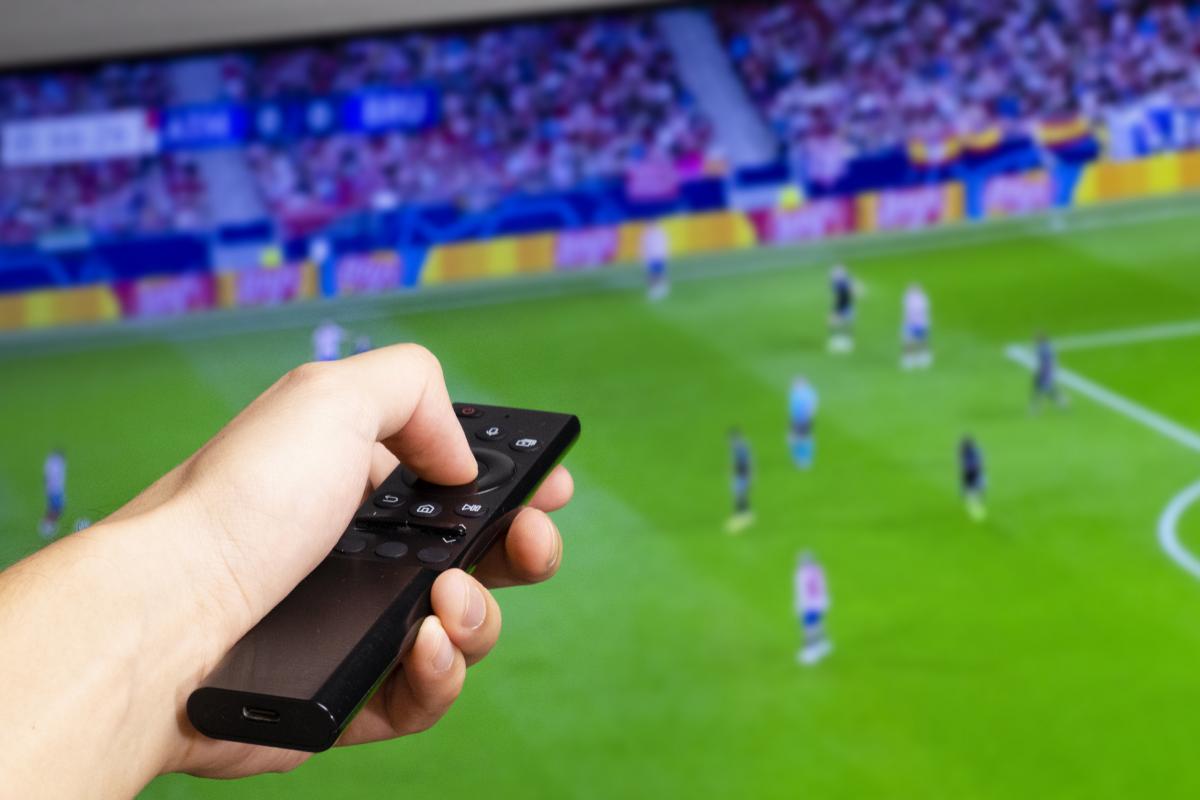 Una persona viendo el fútbol en la televisión.