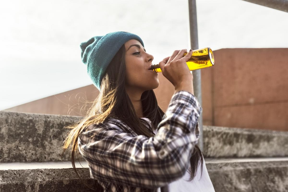 Una joven, vestida como los modelos de los catálogos de Inditex, bebe una cerveza.