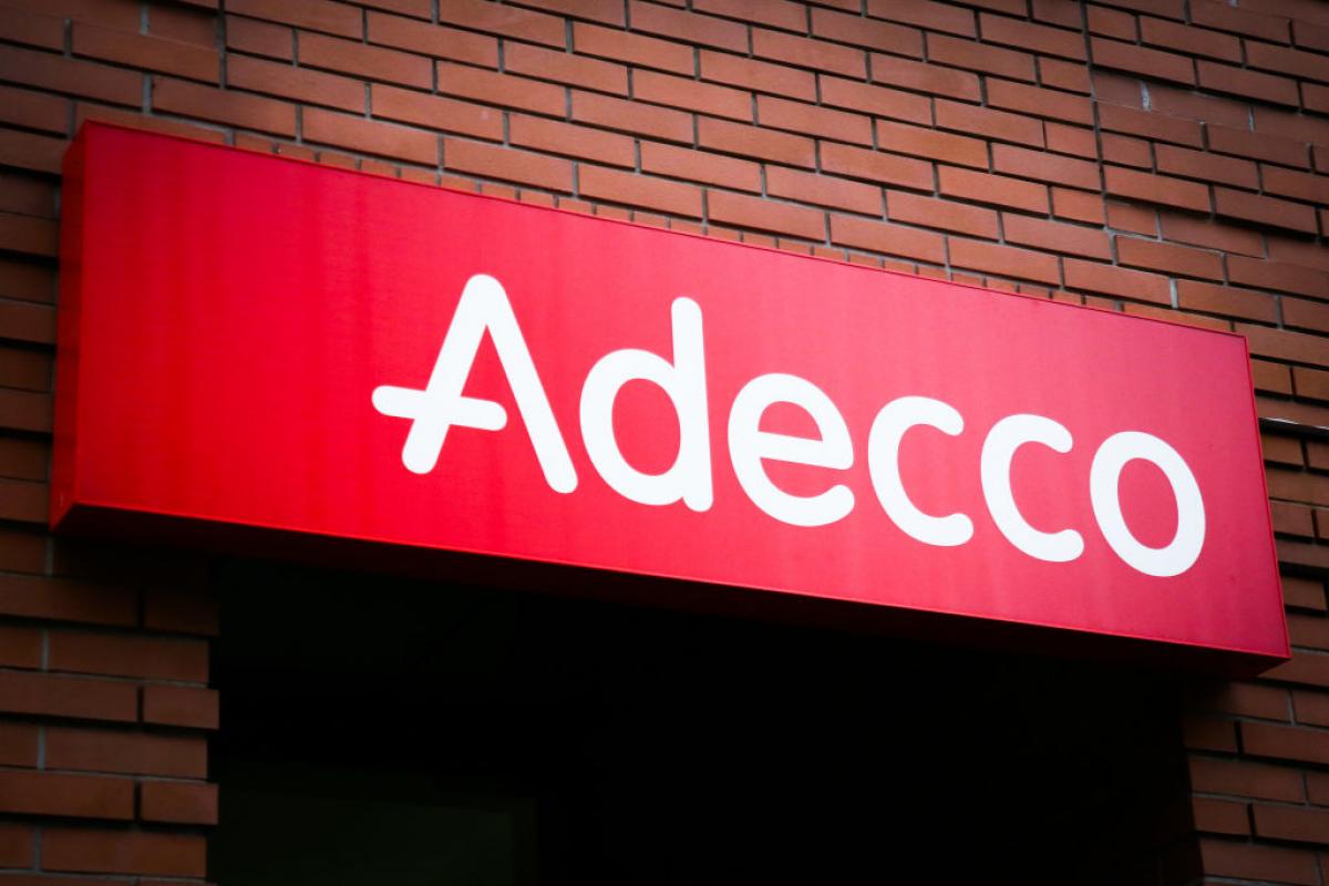 Logotipo de Adecco situado en la puerta de acceso de una oficina de la compañia.